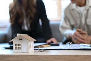 house-model-on-wooden-table-and-financial-adviser-2023-11-27-04-54-43-utc
